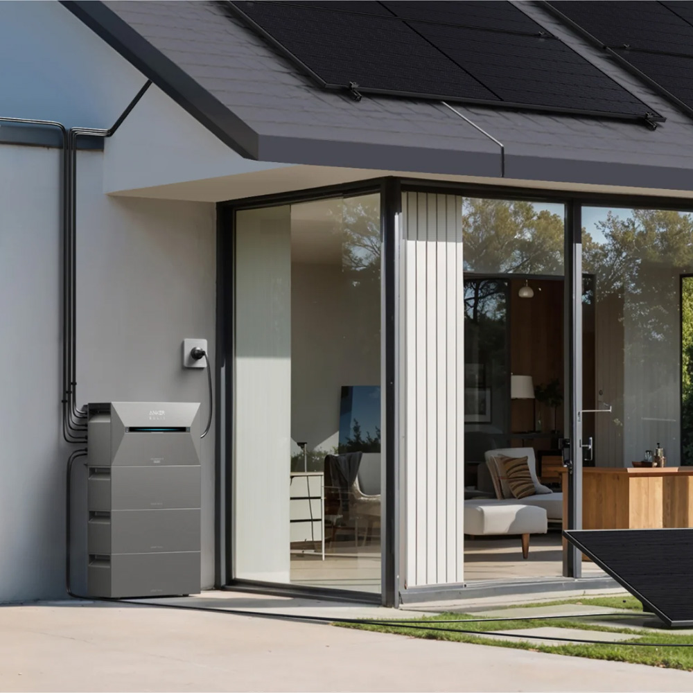 Solarspeicher mit mehreren Batteriemodulen an der Außenwand eines Hauses, verbunden mit PV-Modulen auf dem Dach