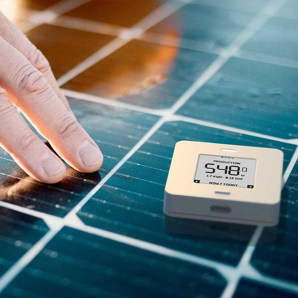 Weißer, quadratischer myStrom WiFi Button Max mit Taste, Display und LED-Leuchte, abgelegt auf einem Solarmodul
