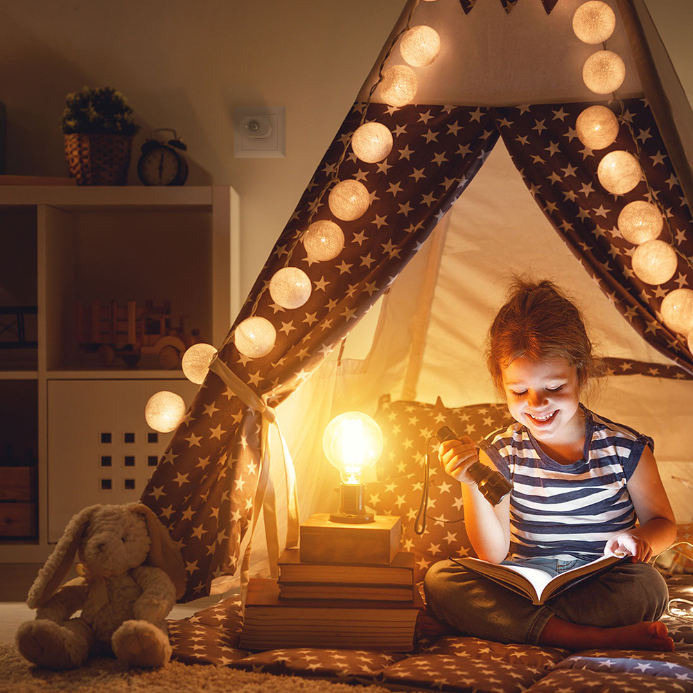 MyStrom WiFi Motion Sensor in einer Steckdose; davor sitzt ein Kind, das ein Buch liest mit einer angeschalteten Lampe
