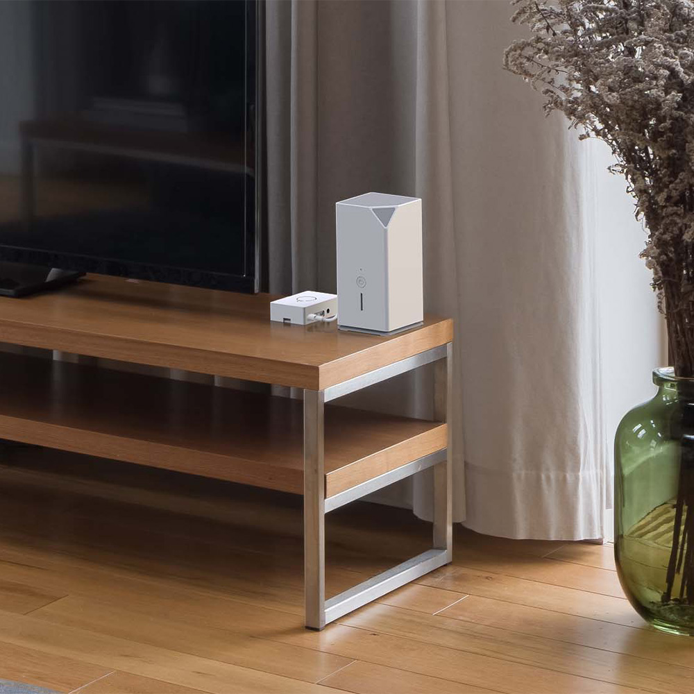 Weißes myStrom Home OS Smart-Home-System neben einem Fernseher auf einem Tisch stehen