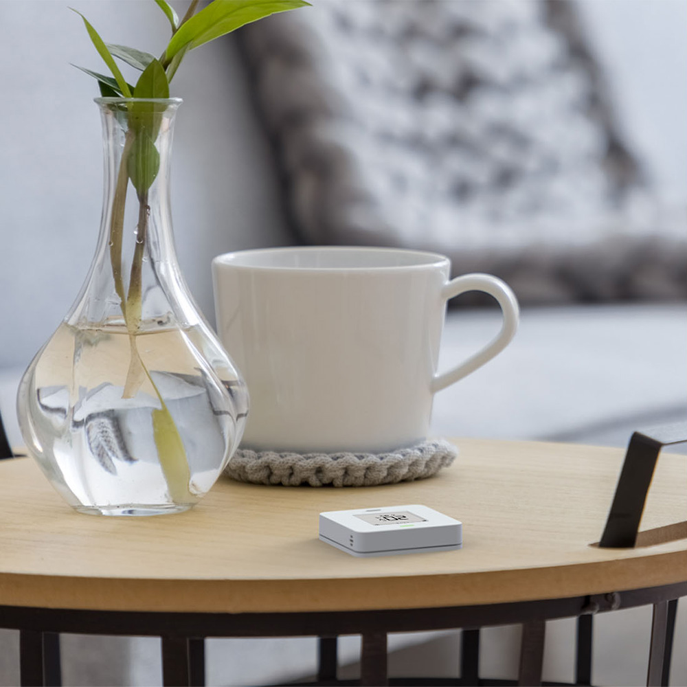 Weißer, quadratischer myStrom WiFi Button Max mit Taste, Display und LED-Leuchte auf einem Tisch