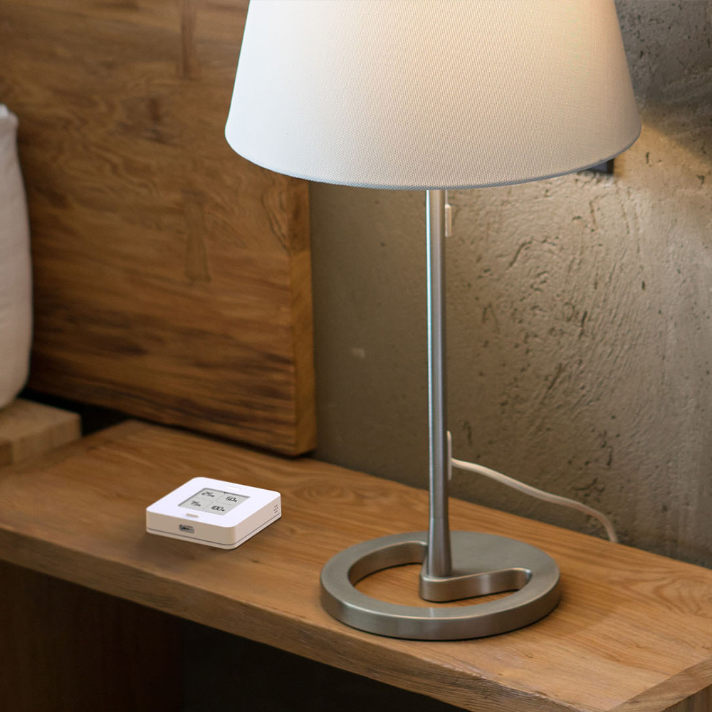 Weißer, quadratischer myStrom WiFi Button Max mit Taste, Display und LED-Leuchte auf einem Nachtkästchen
