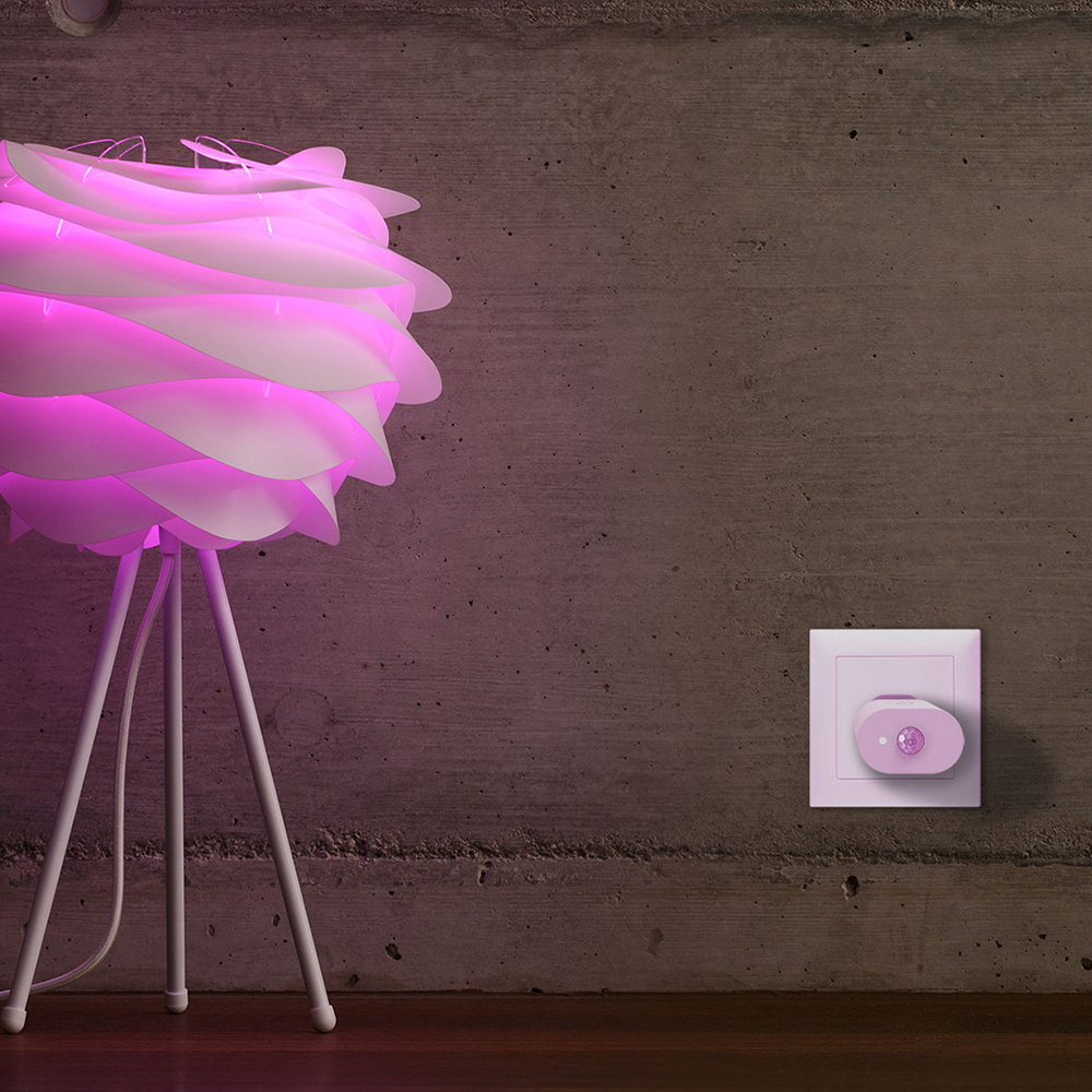 MyStrom WiFi Motion Sensor in einer weiße Wandsteckdose neben einer Lampe, die lila leuchtet